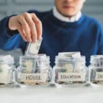 Man putting money in separate savings buckets that he learned from Think and Talk Money
