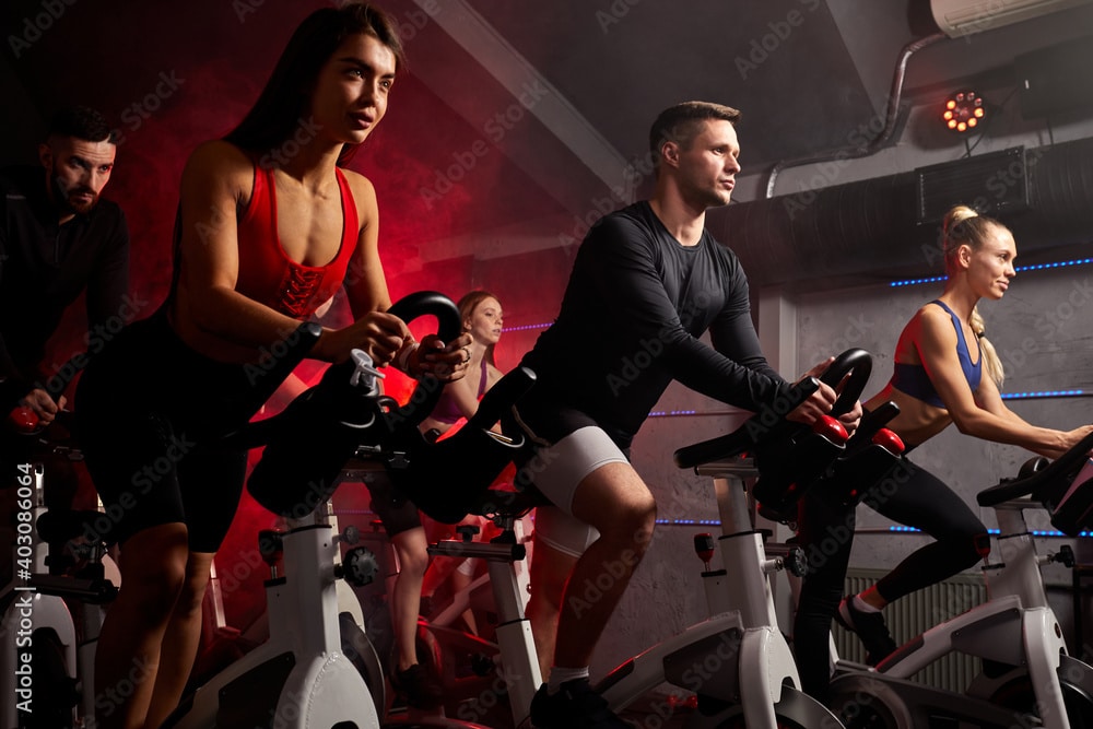 men and women biking in gym, spinning in health club, thinking about their money and their lives.