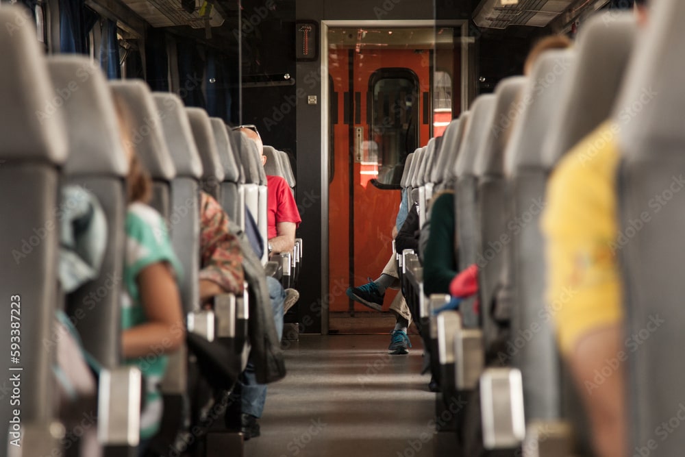 Seats of a passenger car in a European train with 1 of 3 people sitting on it not able to pay their bills for one month if they lost their jobs.