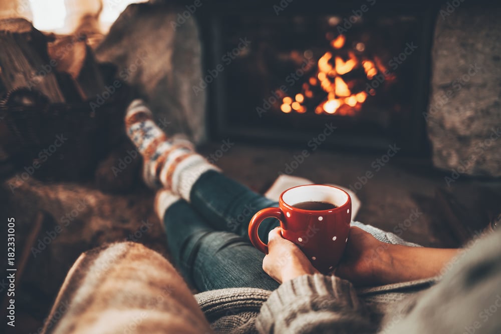Woman in woollen socks by the fireplace after being comfortable with money by visiting financial freedom blog, Think and Talk Money.