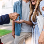 Young happy couple talking with real estate agent and buying a new house after reading Think and Talk Money and not waiting for mortgage rates to drop.