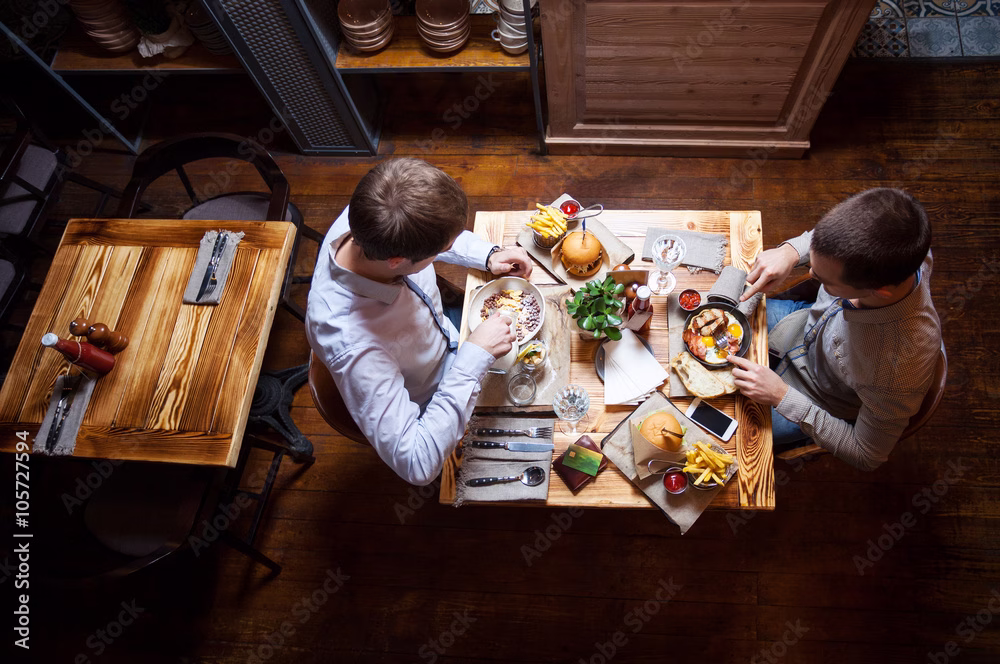 Two men eating out in cafe or restaurant talking about financial independence as learned on Think and Talk Money.