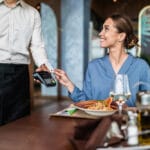 Wman paying for her order with a credit card in a restaurant so she can easily stay on budget tracking two simple numbers.