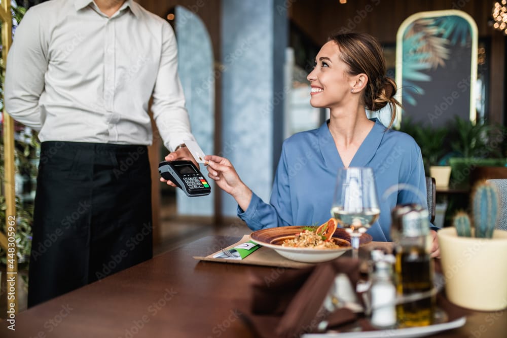 Wman paying for her order with a credit card in a restaurant so she can easily stay on budget tracking two simple numbers.