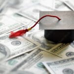 Money and graduation hat illustrating that debt from student loans and financial freedom go hand-in-hand for professionals.