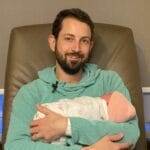 Matthew Adair, founder of Think and Talk Money, holding his baby girl and reminded of his Money Why, which is to be good with money for his family.