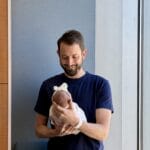 Matthew Adair, founder of Think and Talk Money, holding his baby and recalling that he started his journey to financial freedom more than a decade ago and learned that the journey to financial freedom for lawyers and professionals does not happen over night.
