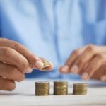 a person stacking coins on top of a table illustrating that investing does not have to be complicated if your mindset is in the right place.
