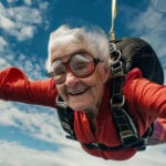 Senior woman enjoying a skydiving experience, freefalling through the sky with a look of exhilaration, illustrating the calm required to get through times of market uncertainty like this.