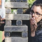 woman playing with wooden blocks illustrating the cost of investing is risk.