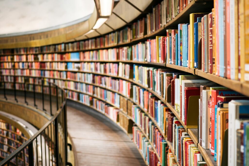 Books on a brown wooden shelf, which includes a money mindset book to help learn about the balance between life and money.