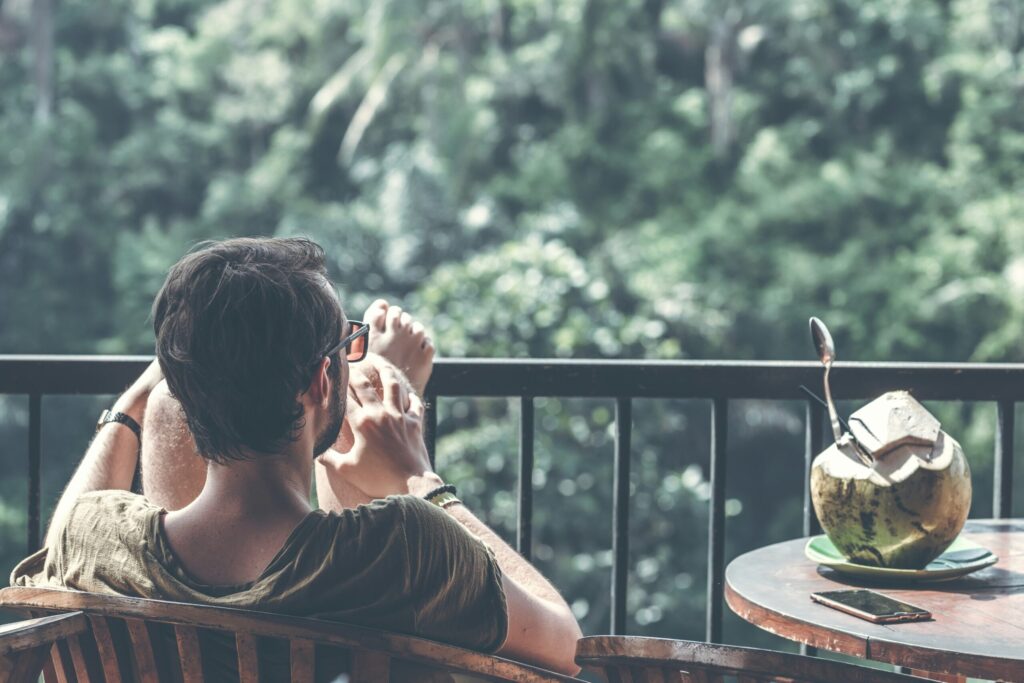 Man with fresh organic coconut relaxing because he invests in index funds as learned on Think and Talk Money.