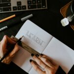 person writing learn on white paper because learning basic stock market terminology make investing in the stock market less intimidating.