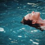 Woman relaxing on water in sunlight because she invests in index funds so doesn't worry about the markets.