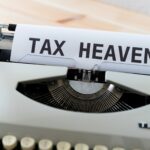 A close up of a typewriter with a tax heaven sign illustrating that investing in real estate provides unmatched tax benefits.