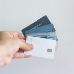 A person holding credit cards against a white background wall wondering whether he should keep two sapphire reserve credit cards.