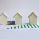 Three small houses sitting on top of a piece of paper illustrating how to generate long-term wealth through appreciation in real estate.