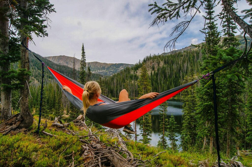 woman on hammock near river relaxing because she invested for her future retirement while saving for college.