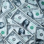 Dollar bills spread out suggesting that you need to get your personal finances in order before investing in real estate.