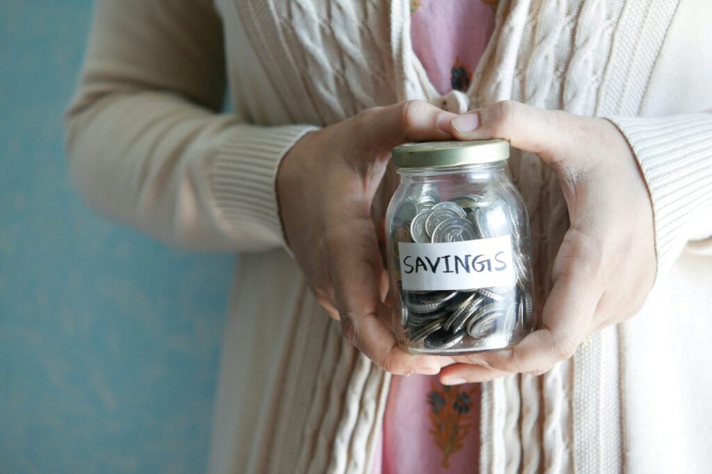 A woman holding a jar with savings written on it suggesting you need to get your personal finances in order before investing in real estate.