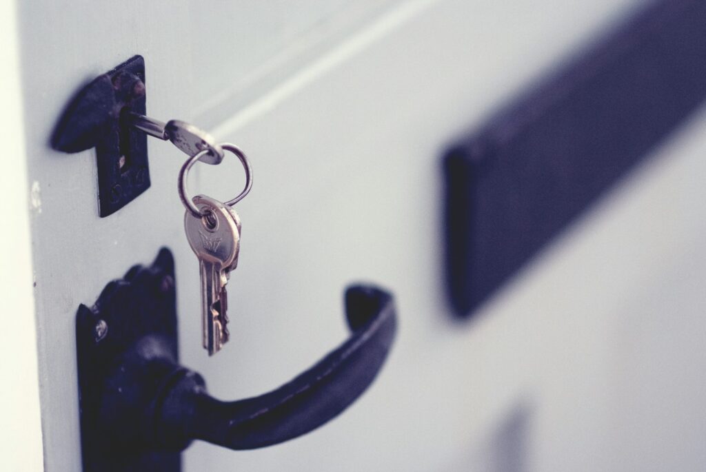 Key in white door with black handle representing what is possible when you have a good real estate team.