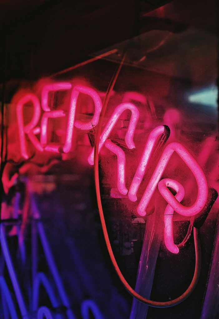 red and blue repair neon light signage indicating that owning rental properties requires repairs and is not a source of passive income.