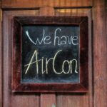 wood chalkboard sign saying we have air conditioning reflecting that as a landlord, you don't earn passive income.