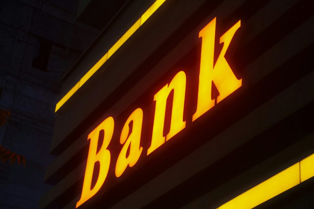 a bank sign lit up in the dark as a reminder to always evaluate your banking relationships.