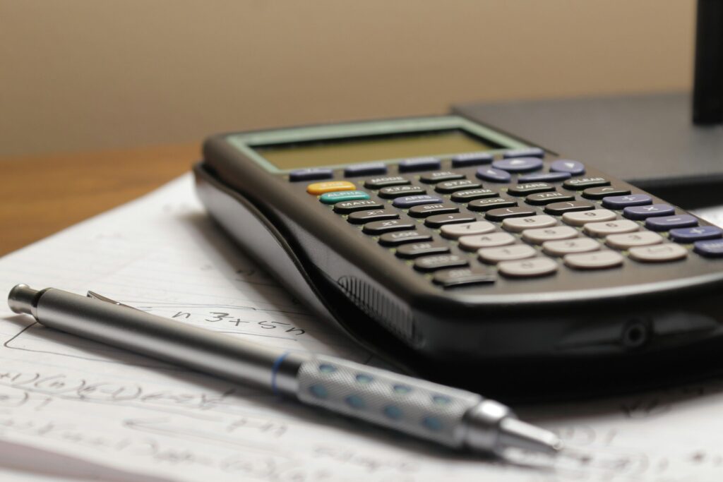 a calculator and a pen on top of paper to show you how to use CoCROI and ROI to evaluate different investments.