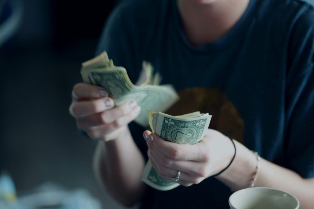 woman counting dollar bills indicating the choices we all have to make with our spending and budget.