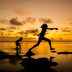 silhouette of girl and boy at the beach indicating when you have enough saved for retirement you can pivot to other pursuits because of Coast FIRE.