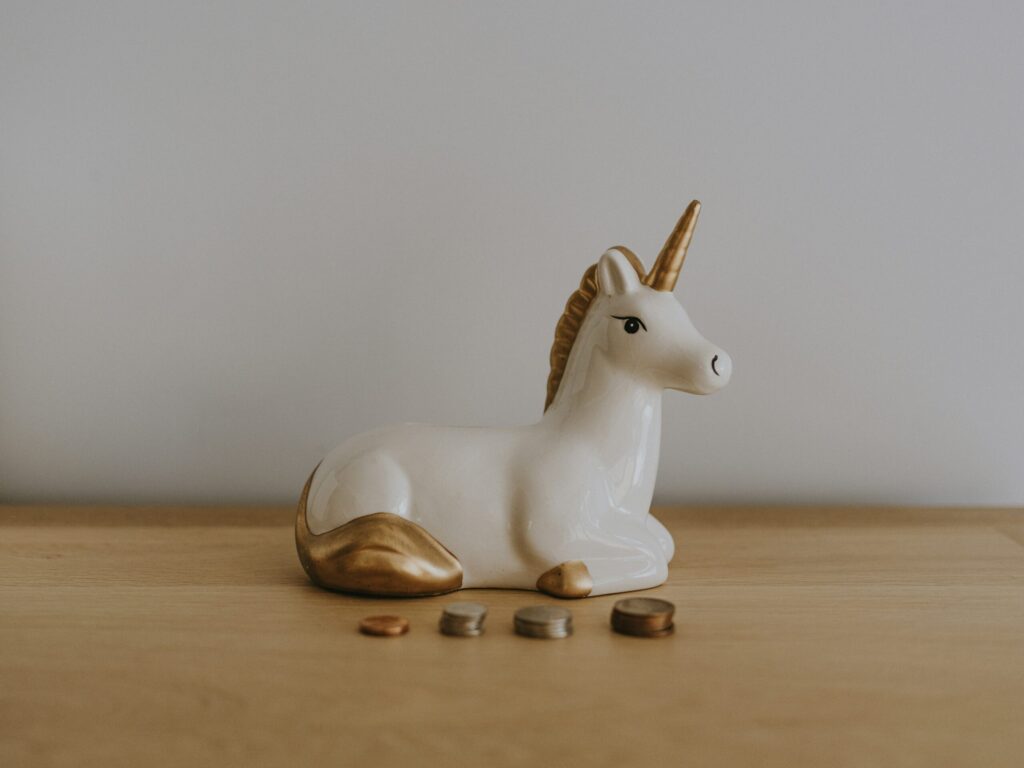 Unicorn money box and coins stacked for saving money for a down payment.