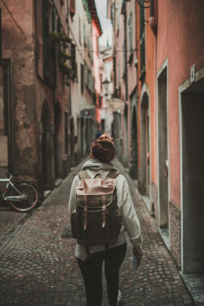 woman walking on street surrounded by buildings and thinking about own rental properties.
