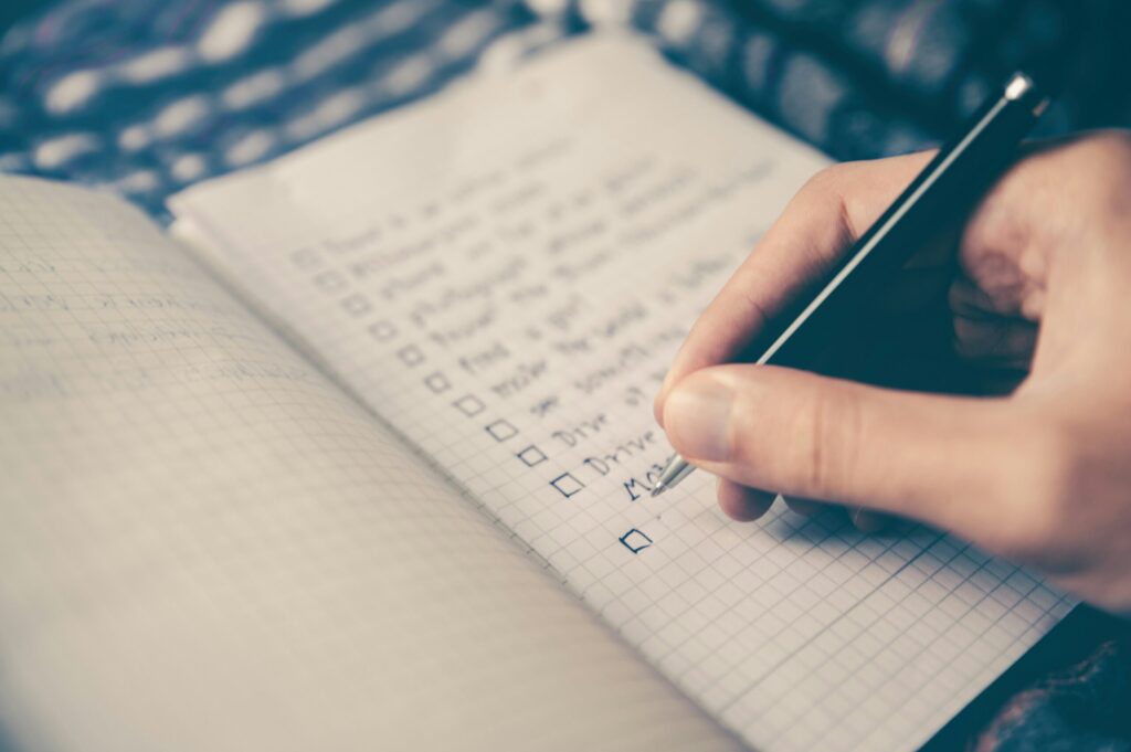 a note pad and person writing goals with black pen to illustrate the importance of not ignoring your Later Money goals.