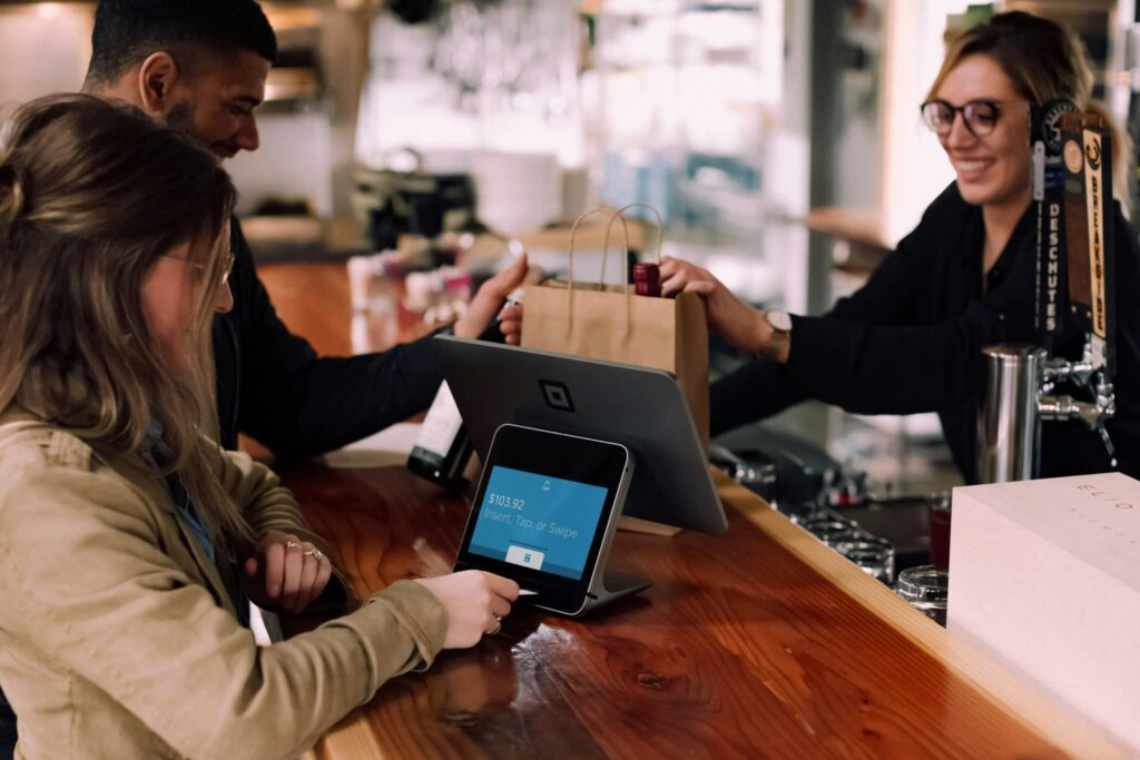 people using credit card devices on brown table to use points instead of cash back