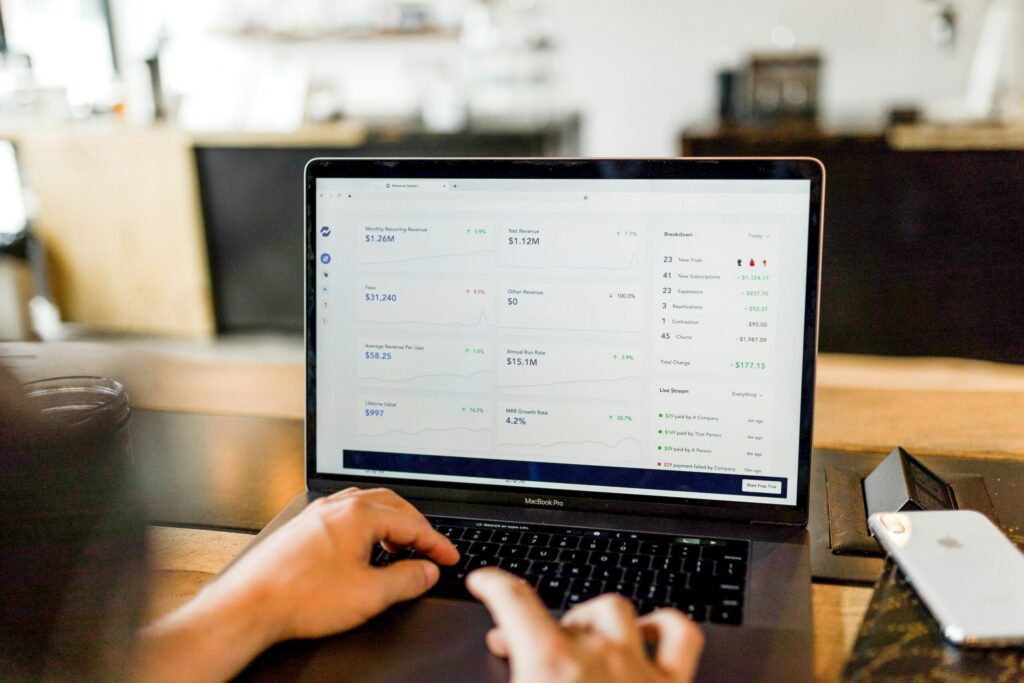 person using MacBook reflecting that the bills still need to be paid when you are furloughed, which is why emergency savings and parachute money are so important.