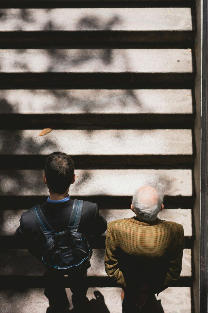 young man and older man standing at bottom of stairs representing the importance of tracking your net worth.