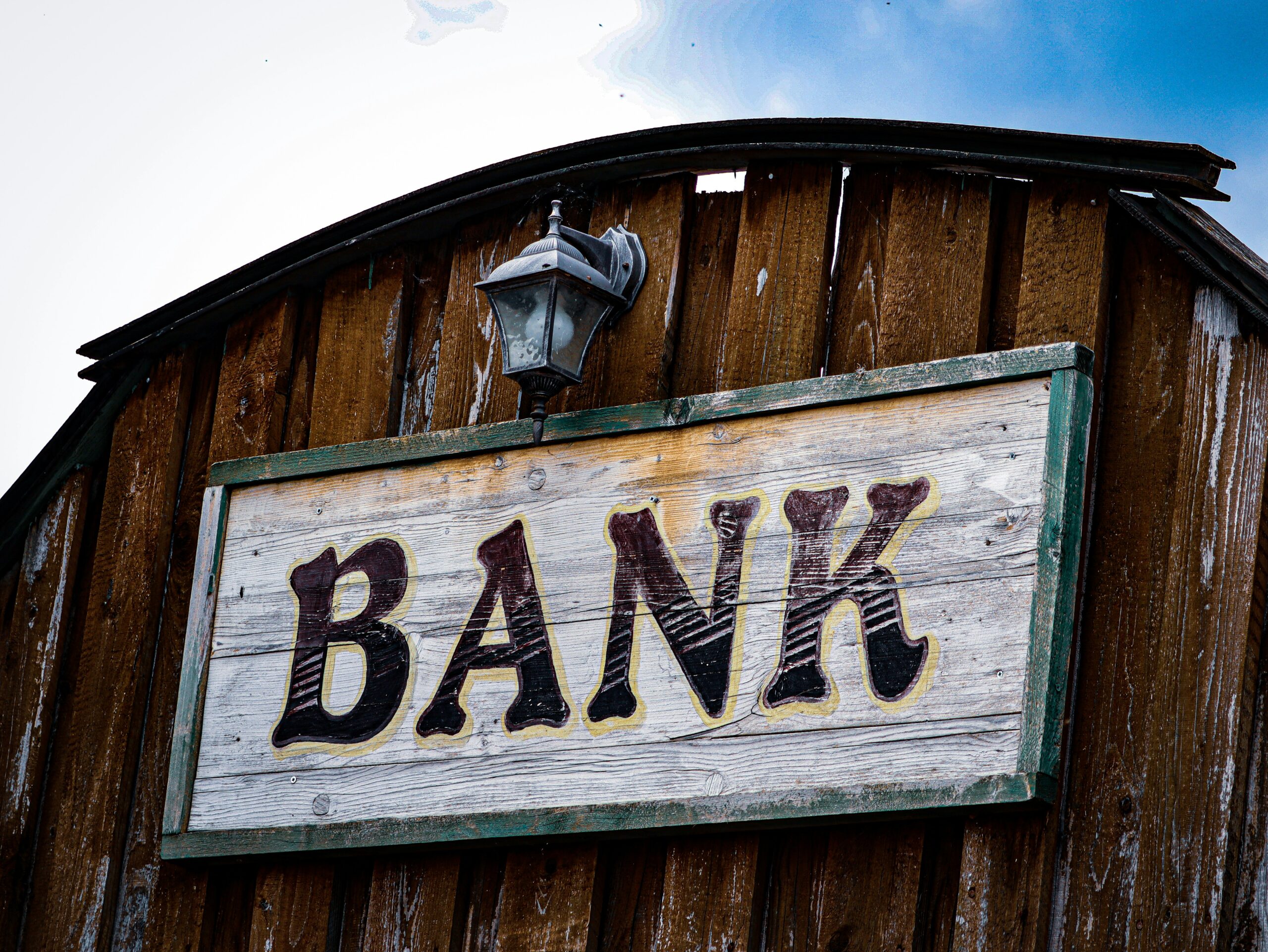 bank sign on the side of wooden building reflecting the credit card tip of not letting the bans get richer off of you.