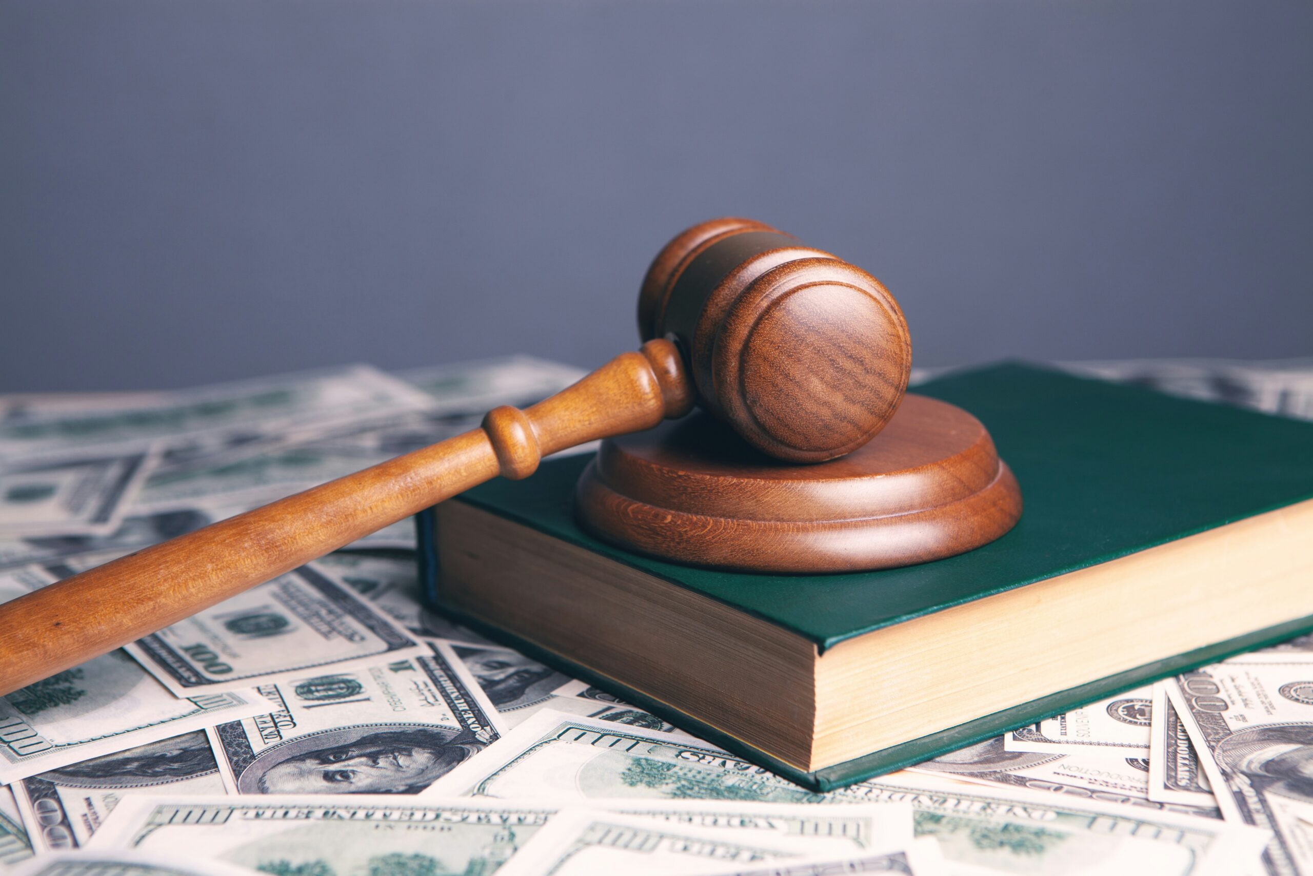 brown gavel and green book and money indicating that if you're a lawyer in debt, you make plenty of money and the problem is not your income.
