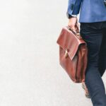 brown briefcase held by man but not going to work because he was furloughed, which is a good reminder to have emergency savings and parachute money.