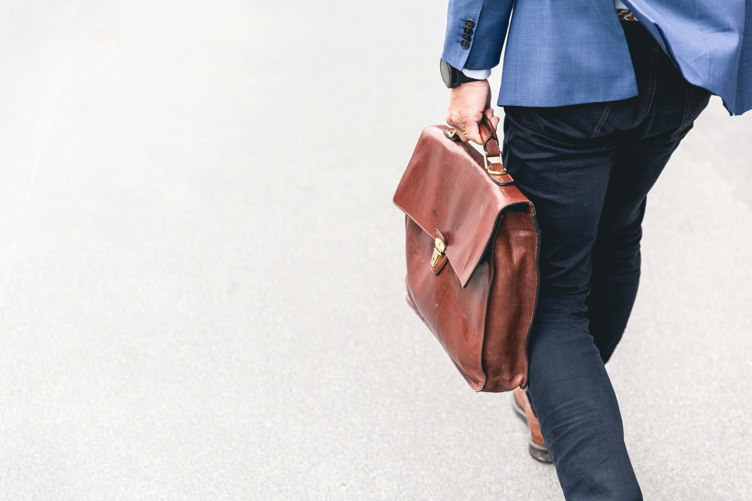 brown briefcase held by man but not going to work because he was furloughed, which is a good reminder to have emergency savings and parachute money.