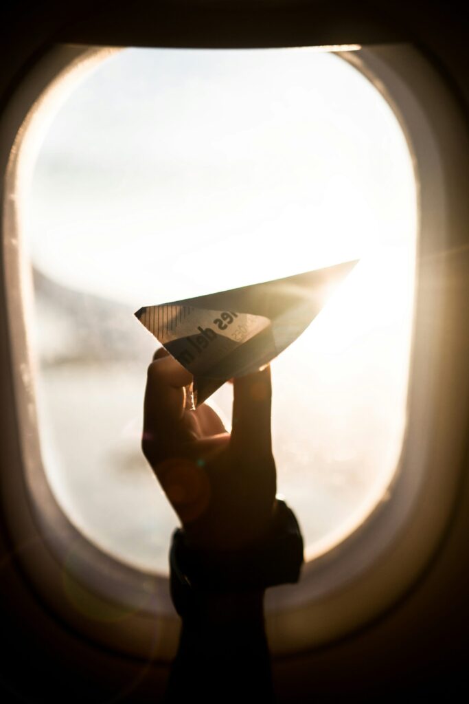 paper airplane in a window of airplane reflecting that we need to have a plan with our money before dreaming on investments.
