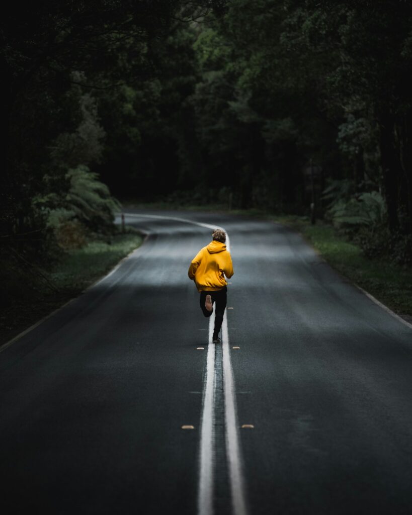 person in yellow jacket running down a road showing what it means to hustle to financial freedom.