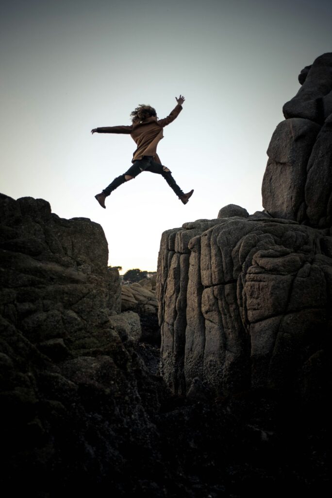 person jumping from cliff to cliff illustrating the concept of reasonable investment risk for young people as shown by the Think and Talk Money Compound Interest Calculator.