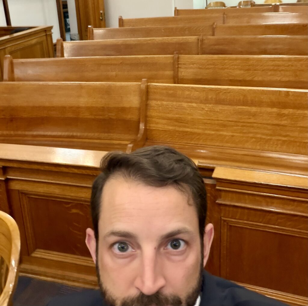 Think and Talk Money founder Matt Adair sitting alone in a courtroom feeling invisible like being in the invisible middle on his financial journey.